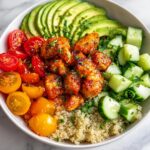A vibrant Fresh Summer Veggie Chicken Bowl featuring glazed chicken, sliced avocado, cherry tomatoes, cucumbers, and quinoa.