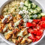Overhead view of a vibrant Greek Chicken Summer Bowl featuring grilled chicken, quinoa, tomatoes, cucumbers, and feta.