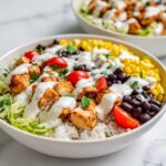 Close-up of a vibrant Greek Yogurt High Protein Taco Bowl featuring seasoned chicken, rice, corn, black beans, and creamy dressing.