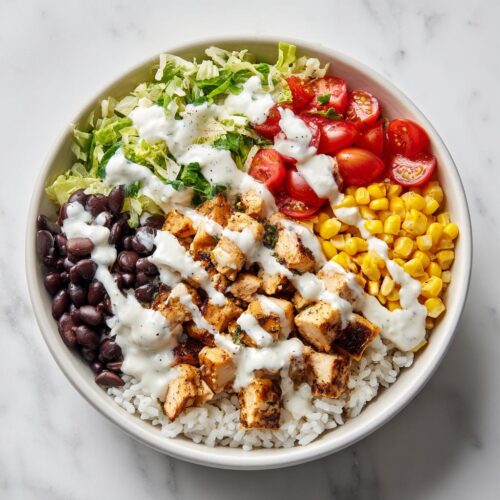 Overhead view of a vibrant Greek Yogurt High Protein Taco Bowl with rice, chicken, black beans, corn, tomatoes, and lettuce.