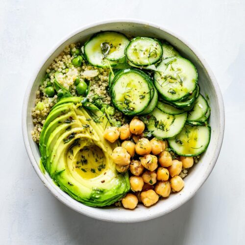 Overhead view of a Healthy Summer Lunch Bowl featuring quinoa, sliced avocado, chickpeas, and cucumbers.