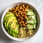 Overhead view of a vibrant Healthy Summer Lunch Bowl featuring quinoa, sliced avocado, roasted chickpeas, and cucumber.