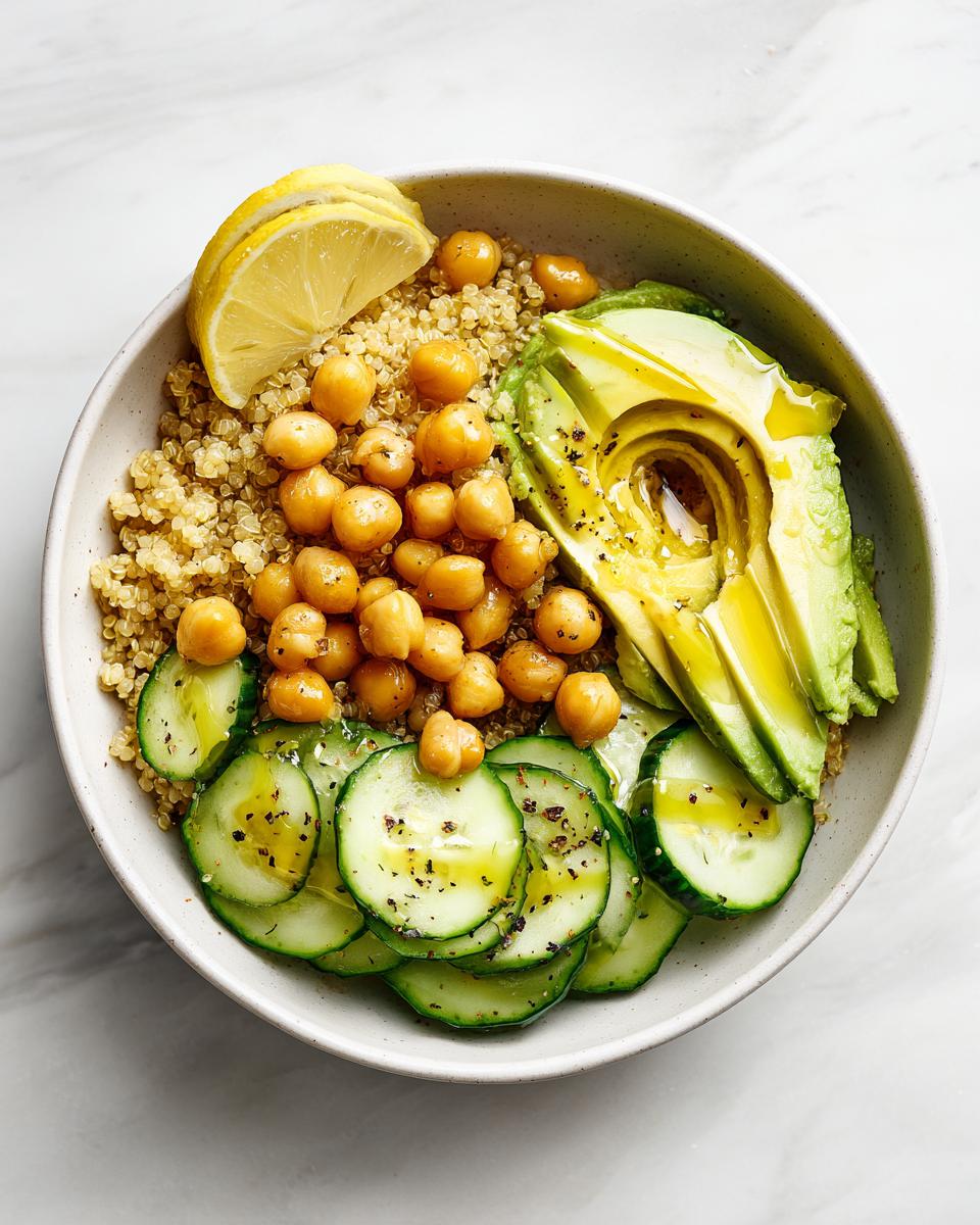 Overhead view of a Healthy Summer Lunch Bowl featuring quinoa, chickpeas, sliced avocado, and cucumbers.