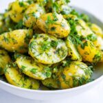Close-up of bright yellow potatoes tossed generously with fresh green herbs in an Herb Potato Salad with Olive Oil.