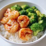 Close-up of a High Protein Summer Shrimp Bowl featuring glazed shrimp, bright green broccoli florets, and white rice in a bowl.