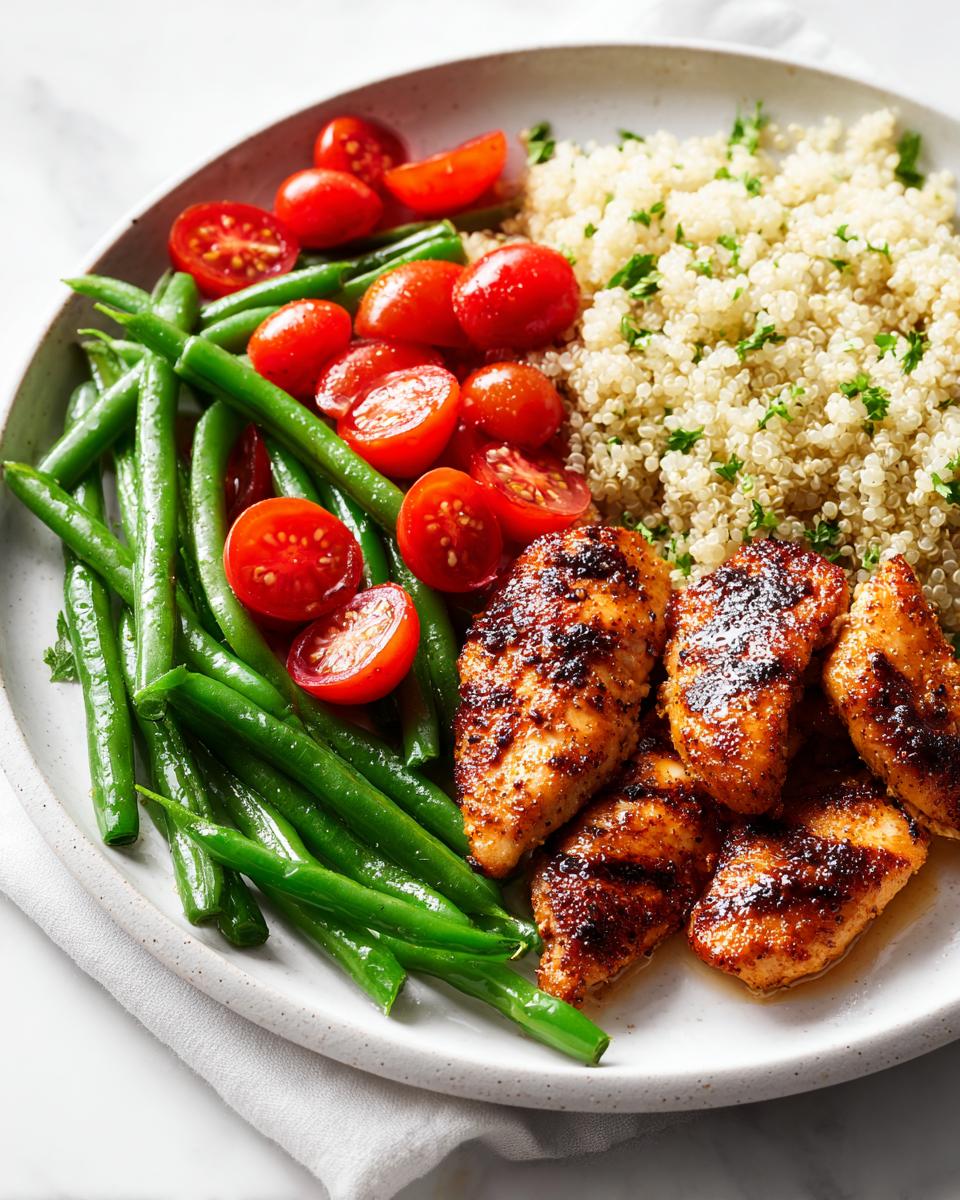 Plate featuring seasoned chicken tenders, bright green beans, halved cherry tomatoes, and quinoa for a Light Chicken Dinner Summer.