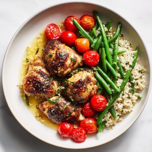 Overhead view of a Light Chicken Dinner Summer plate featuring pan-seared chicken thighs, green beans, cherry tomatoes, and quinoa.