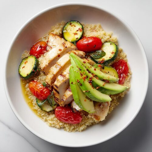 Overhead view of a Light Summer Dinner Bowl featuring grilled chicken, avocado, zucchini, and tomatoes over quinoa.