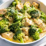 Close-up of Low Carb Creamy Chicken with Broccoli pieces coated in a rich, cheesy sauce in a light-colored skillet.