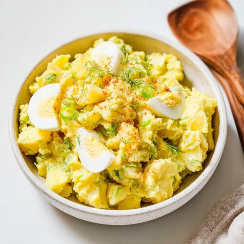 A creamy bowl of Mustard Potato Salad Southern Style garnished with sliced hard-boiled eggs and fresh dill.