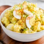 A close-up of creamy Mustard Potato Salad Southern Style garnished with sliced hard-boiled eggs and paprika.