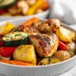 Close-up of roasted chicken pieces mixed with potatoes, zucchini, carrots, and peppers, perfect for Summer Dinner Ideas.