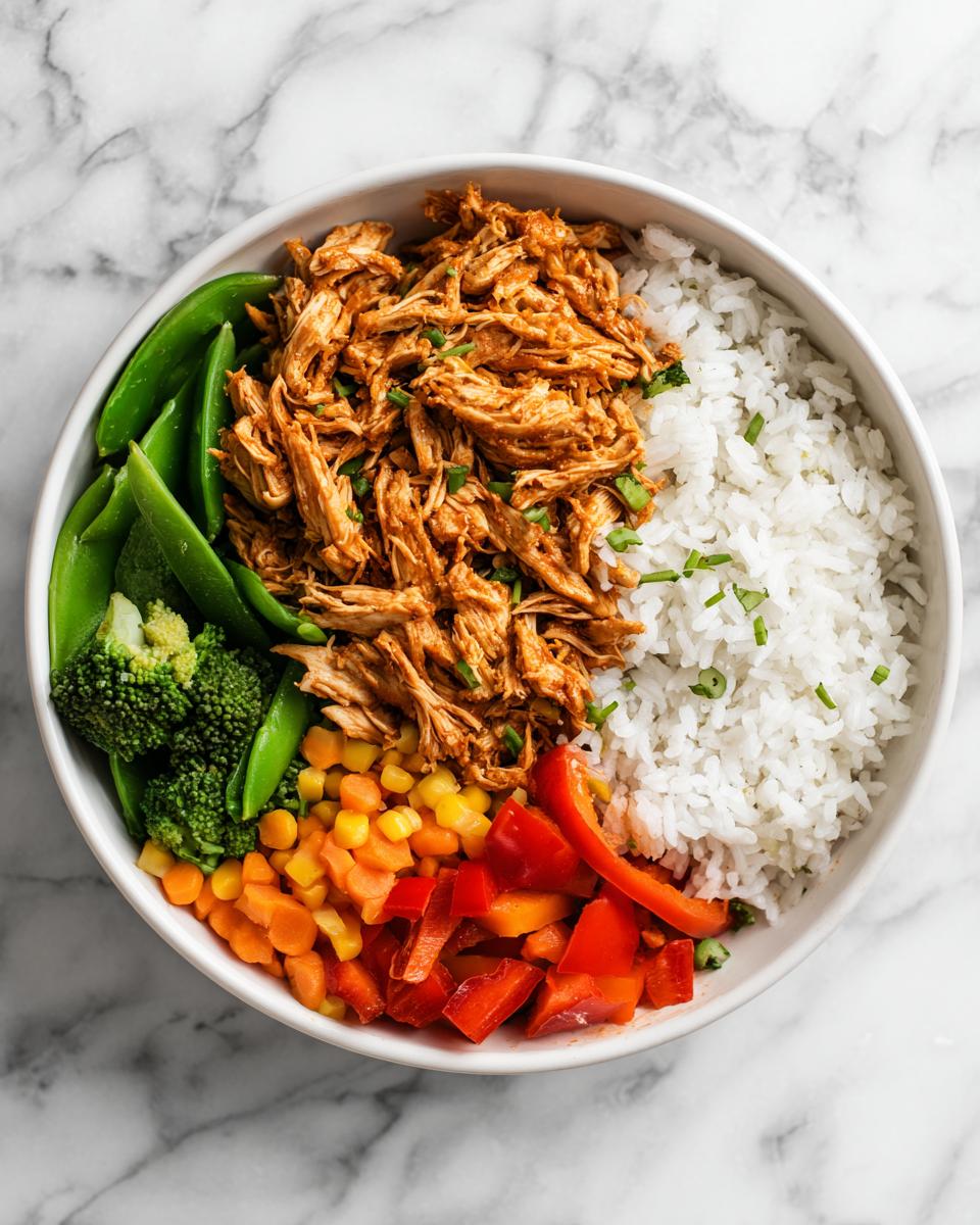 Overhead view of a balanced Chicken Meal Prep Bowls featuring shredded orange-sauced chicken, white rice, and colorful steamed vegetables.