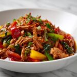 Close-up of shredded meat stewed with colorful peppers and tomatoes, perfect for Summer Crockpot Dinner Ideas.
