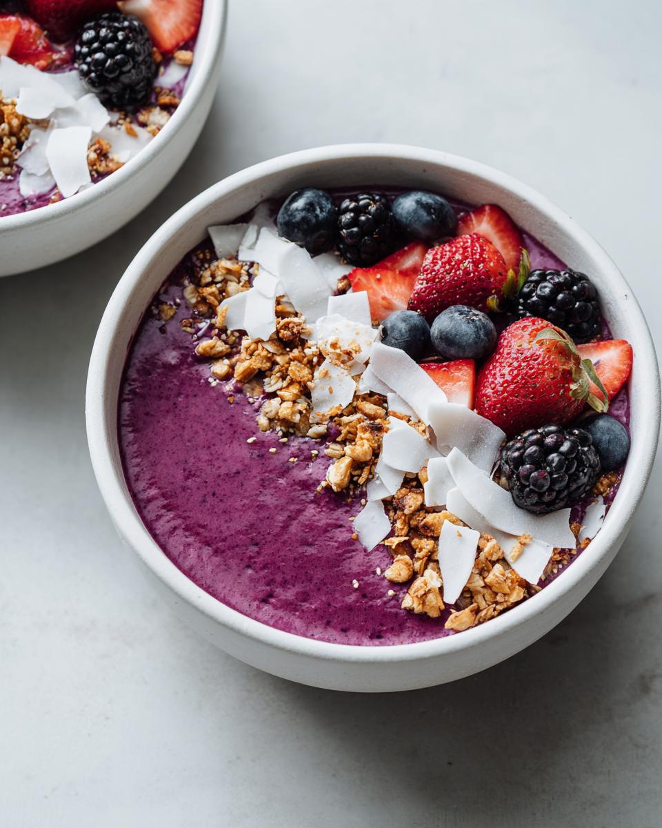 Close-up of a vibrant purple Smoothie Bowl Aesthetic topped with fresh strawberries, blueberries, blackberries, granola, and coconut flakes.