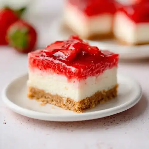Close-up of a single square of Strawberry Cheesecake Bars showing graham cracker crust, creamy filling, and glossy strawberry topping.