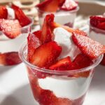 Close-up of layered Strawberry Dessert Mini Cups featuring fresh sliced strawberries and white cream filling.