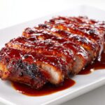 Close-up of sliced Summer BBQ Chicken Plate, heavily coated in a thick, glossy red barbecue sauce.