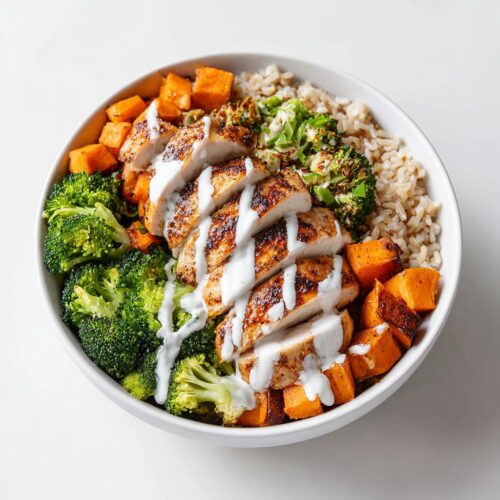 Overhead view of a Summer Bowl Meal Prep featuring sliced grilled chicken, brown rice, roasted sweet potatoes, and broccoli.
