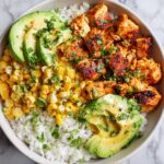 Overhead view of a Summer Chicken Corn Bowl featuring rice, seasoned chicken, corn, and sliced avocado.