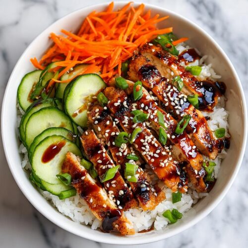 Close-up of a Summer Chicken Rice Bowl featuring sliced glazed chicken over white rice with cucumbers and carrots.