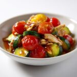 A bowl of shredded chicken mixed with glossy, sliced zucchini and whole cherry tomatoes, perfect for Summer Crockpot Chicken Recipes.