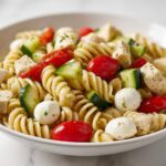 Close-up of a vibrant Summer Pasta Salad with Chicken, featuring rotini pasta, cherry tomatoes, cucumber, and mozzarella balls.