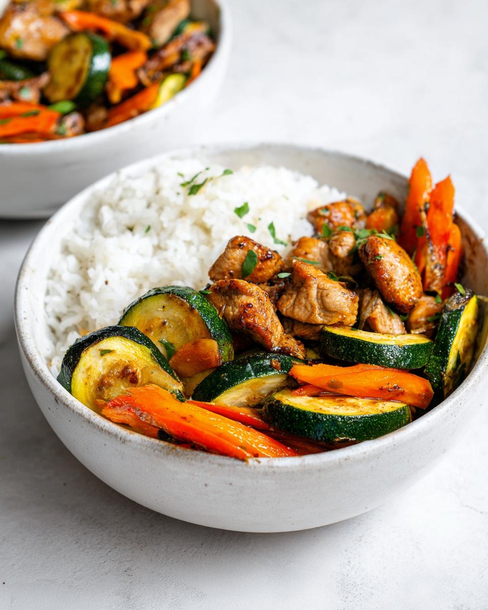 Close-up of a Summer Veggie Bowl with Chicken, featuring rice, sautéed zucchini, and carrots in a white bowl.