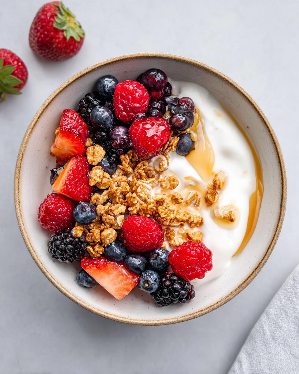Overhead shot of an aesthetic Yogurt Bowl with Fruits, featuring yogurt, mixed berries, granola, and a drizzle of honey.