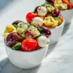 Close-up of individual servings of Italian Dressing Tortellini Salad Cups filled with tortellini, mozzarella balls, tomatoes, and olives.