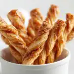 Close-up of several flaky Mini Baked Cinnamon Twists standing upright in a small white bowl.